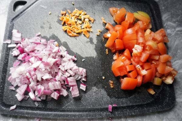 Chopped Onion, pepper and tomatoes on a black cutting board